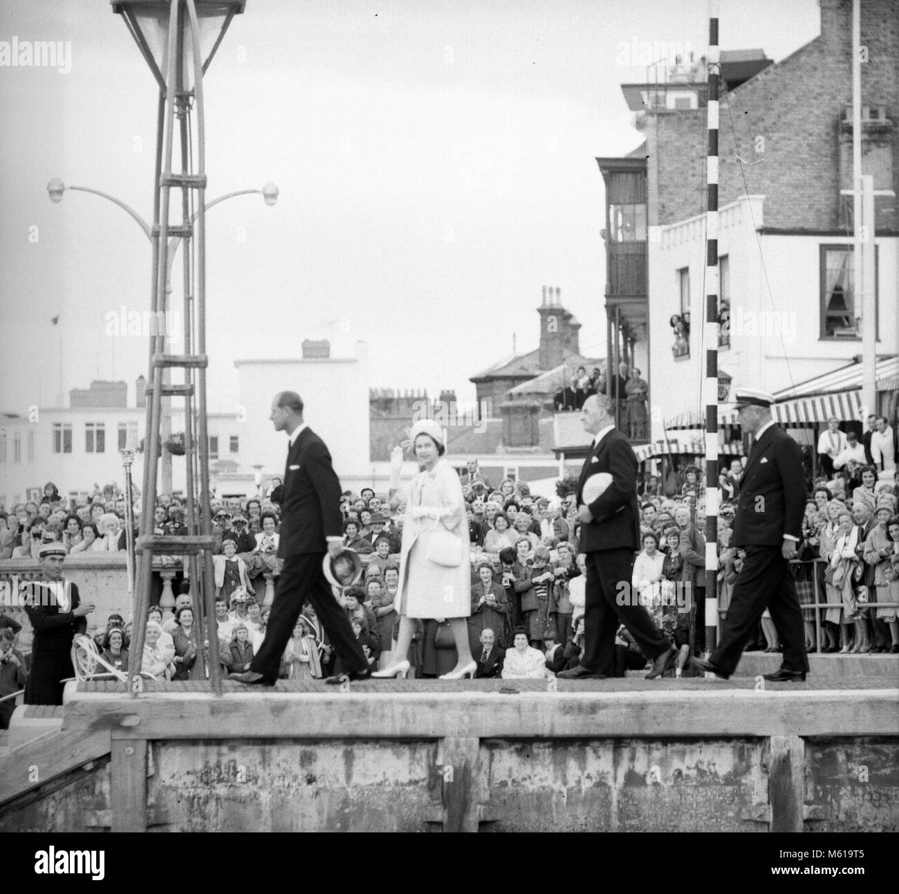 Queen Elizabeth II onde per la folla osservando il suo congedo con il Principe Filippo , Duca di Edimburgo(l) dopo aver frequentato il cocktail party presso il Royal Yacht Squadron durante il primo giorno di una visita di due giorni ad Isola di Wight. Estrema destra è l'ammiraglio della flotta Earl Mountbatten di Birmania. Foto Stock