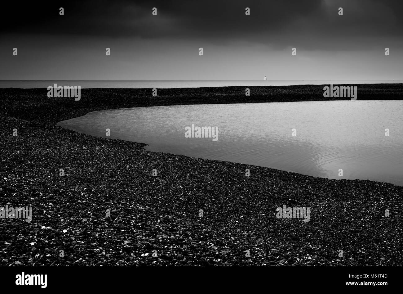 Una immagine di un oscuro e moody colpo di scena alla strada di ciottoli di una spiaggia di ciottoli nel Suffolk, Inghilterra, Regno Unito Foto Stock