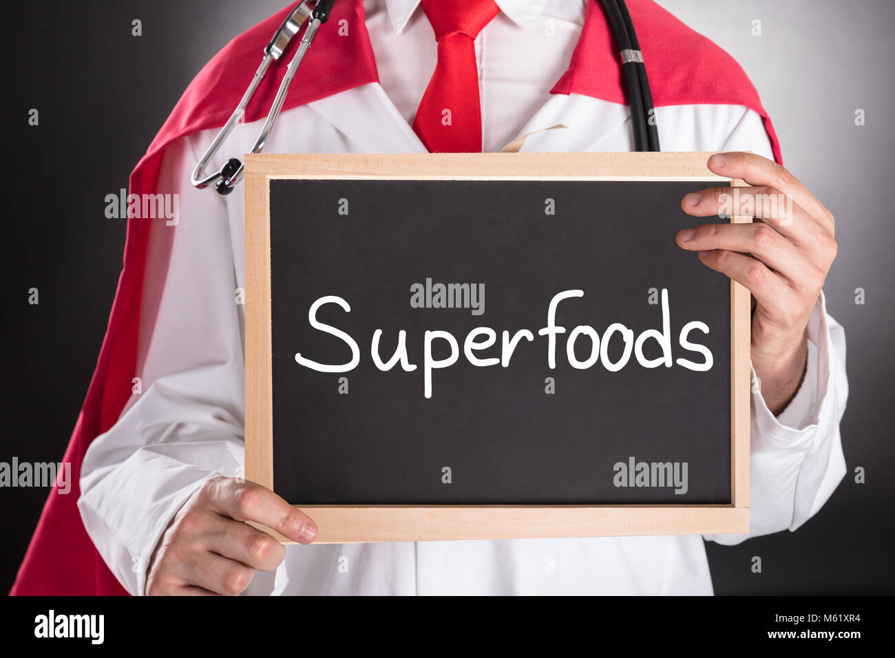 Close-up di supereroe medico azienda piccola lavagna con il testo Superfoods Foto Stock