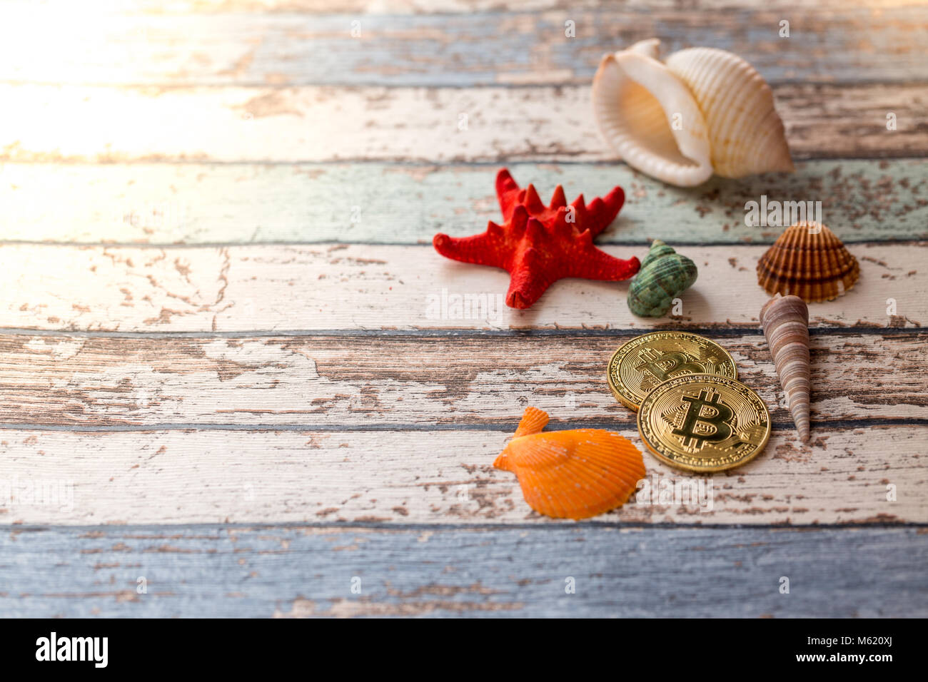 Due golden bitcoins con conchiglie e stelle marine sull'angolo di vintage tavolo in legno Foto Stock