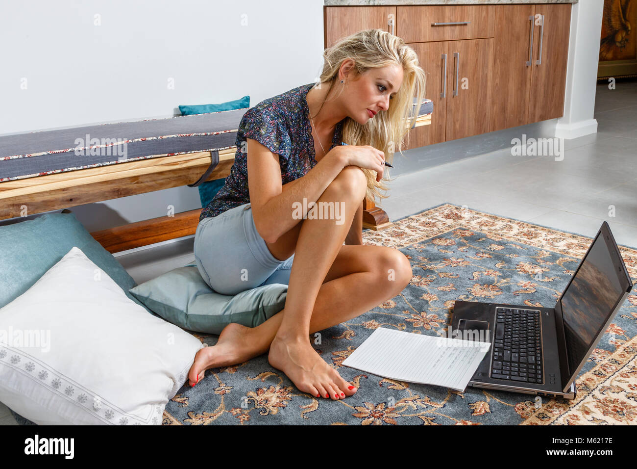 Un casualmente vestito giovane donna adulta con notebook e laptop computer lavora da casa in un ambiente rilassante Foto Stock