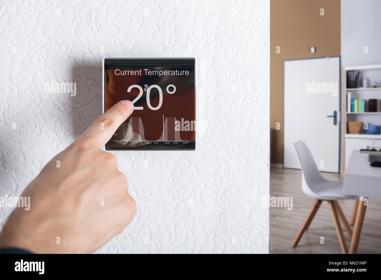Dito toccando termostato digitale Controllore di temperatura a casa Foto Stock
