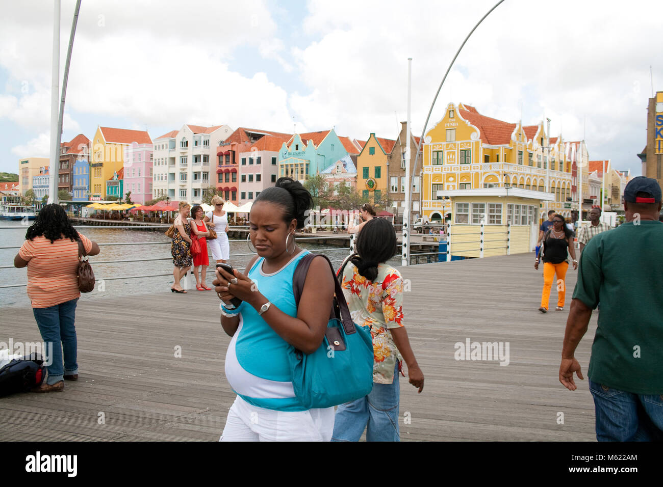 Persone su Queen Emma bridge, dietro la galleria commerciale e colorati di fila di case, Willemstad, Curacao, Antille olandesi, Caraibi, Mar dei Caraibi Foto Stock