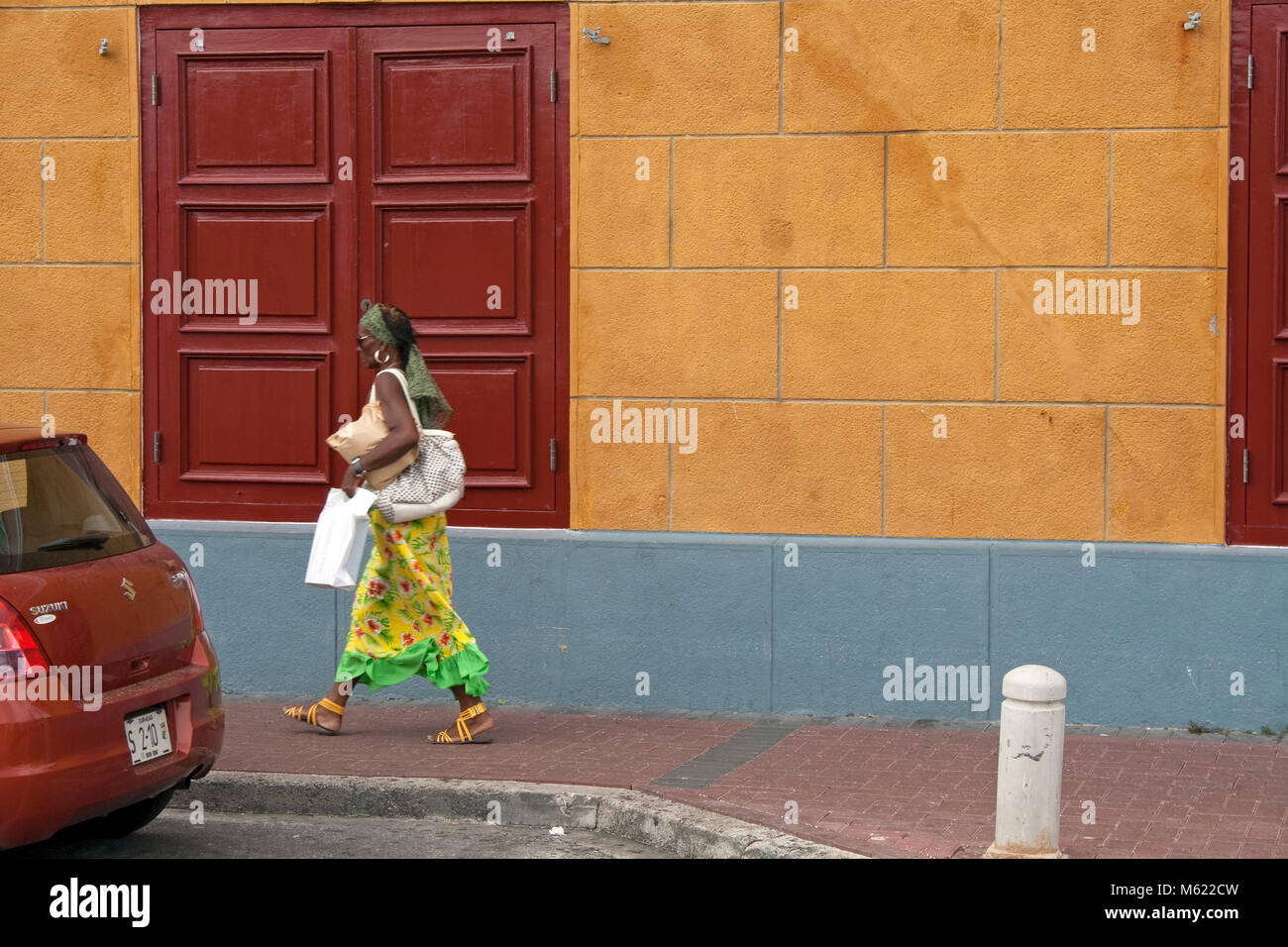 Donna locale a piedi lungo di case coloniali, Punda, Willemstad, Curacao, Antille olandesi, dei Caraibi Foto Stock