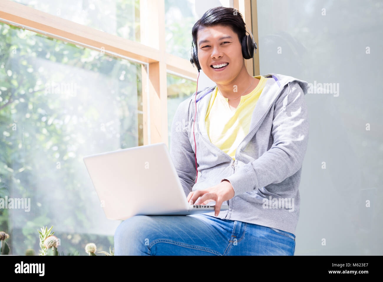 Giovane cinese di indossare abiti casual mentre si utilizza un laptop Foto Stock