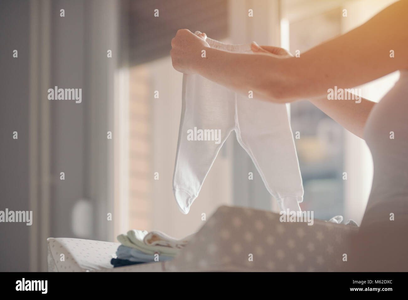 Ordinamento madre neonato Abbigliamento per stirare a casa come parte della routine quotidiana nella cura dei bambini, il fuoco selettivo Foto Stock