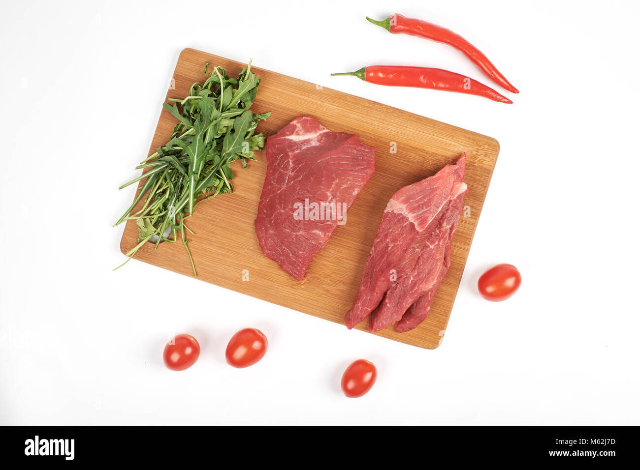 Fette di carne di manzo crudo sul tagliere e verdure isolati su sfondo bianco Foto Stock