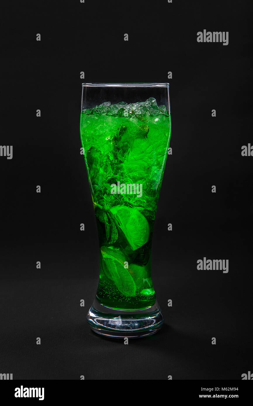 Estate verde drink con succo di limone, lime e menta, ghiaccio isolato su sfondo nero. Prospettiva diretta, fresca e rinfrescante Foto Stock