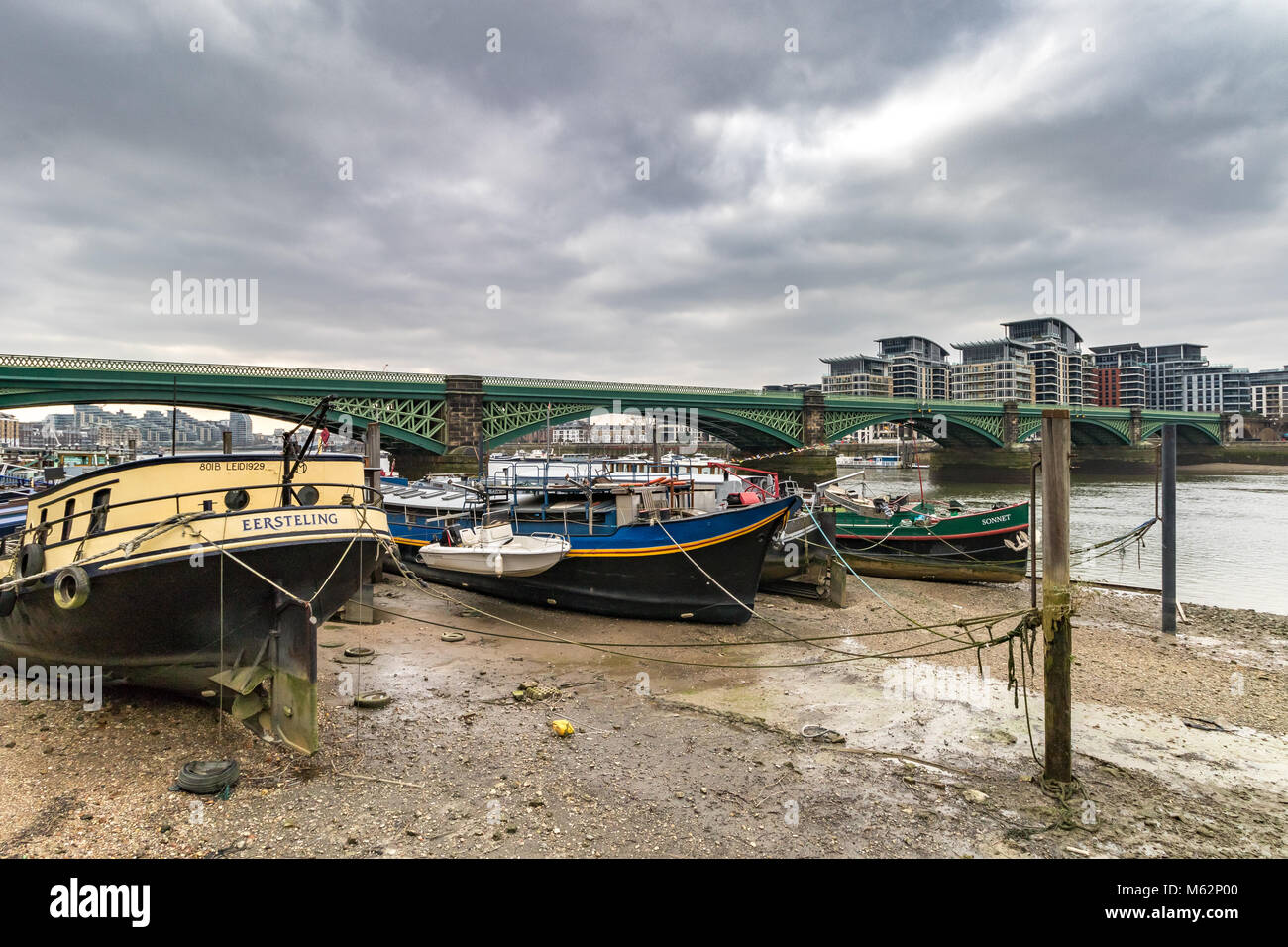 Barche ormeggiate a bassa marea lungo il fiume Tamigi vicino a Battersea Railway Bridge , Battersea , London Regno Unito Foto Stock