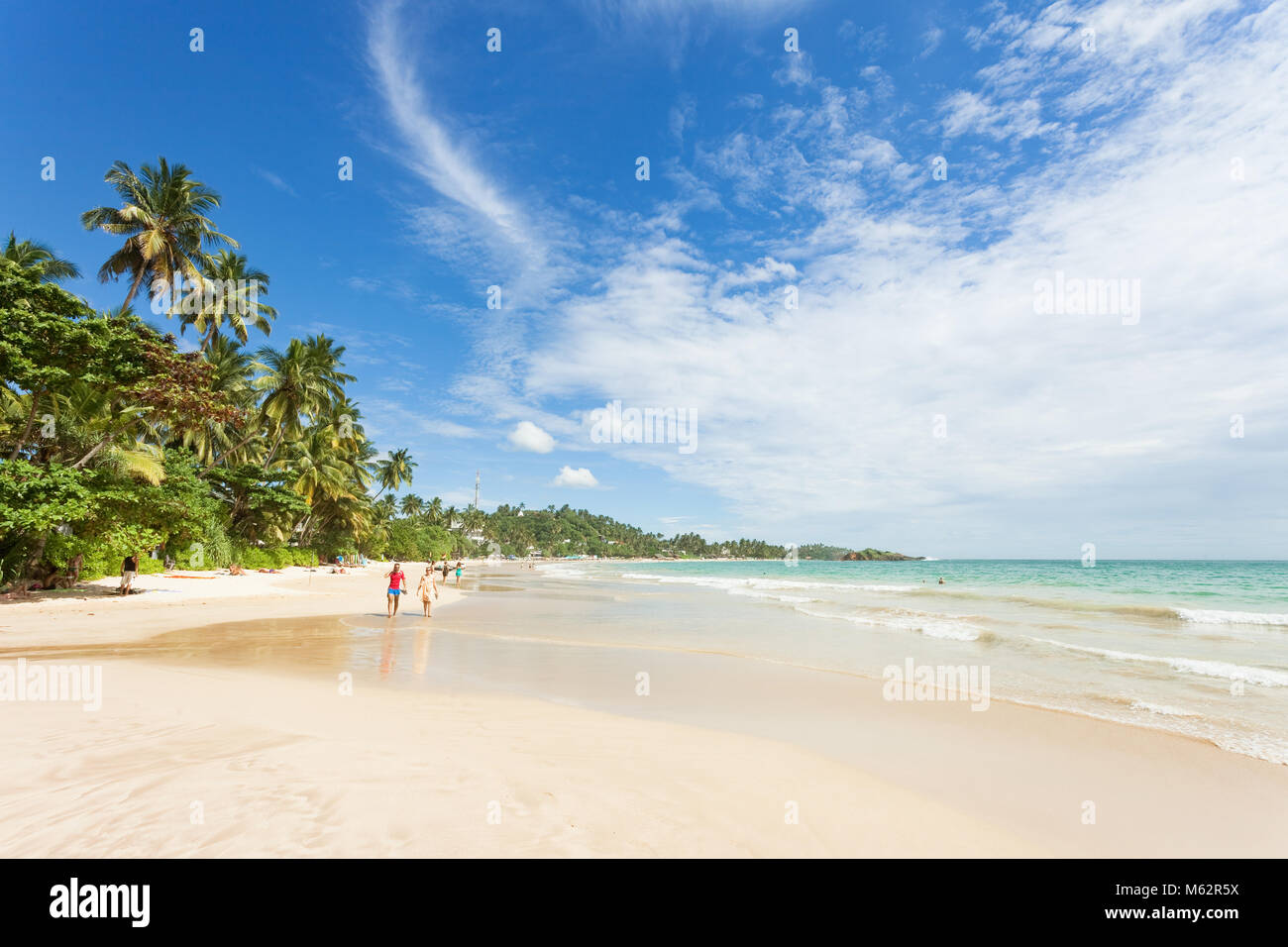 Mirissa Beach, Sri Lanka, Asia - Dicembre 2015 - i turisti a camminare sulla sabbia mentre godendo la vista su tutta la meravigliosa spiaggia di Mirissa Foto Stock