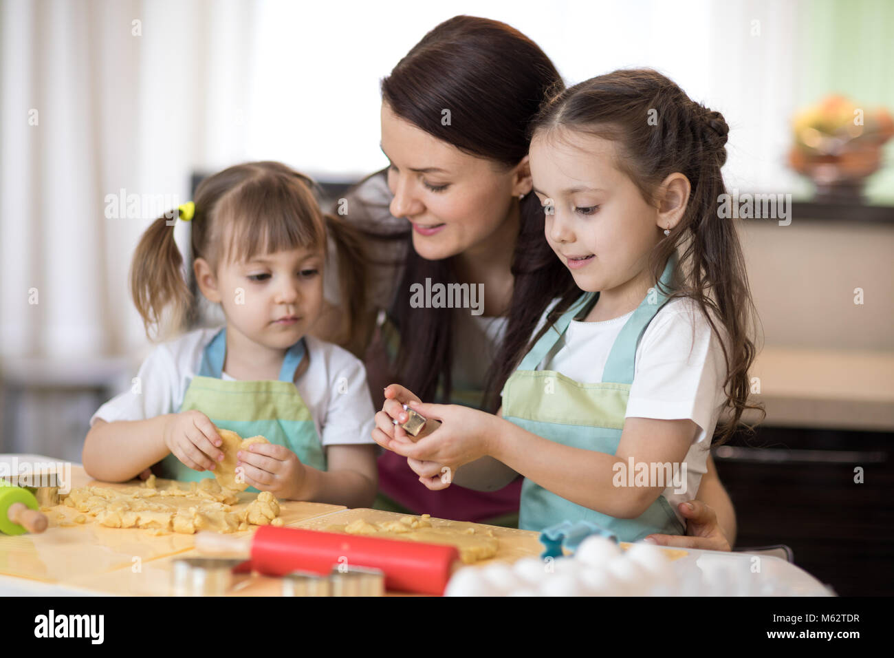 La mamma con il suo 2 e 5 anni sono figlie della cottura in cucina domestica per la festa della mamma Foto Stock