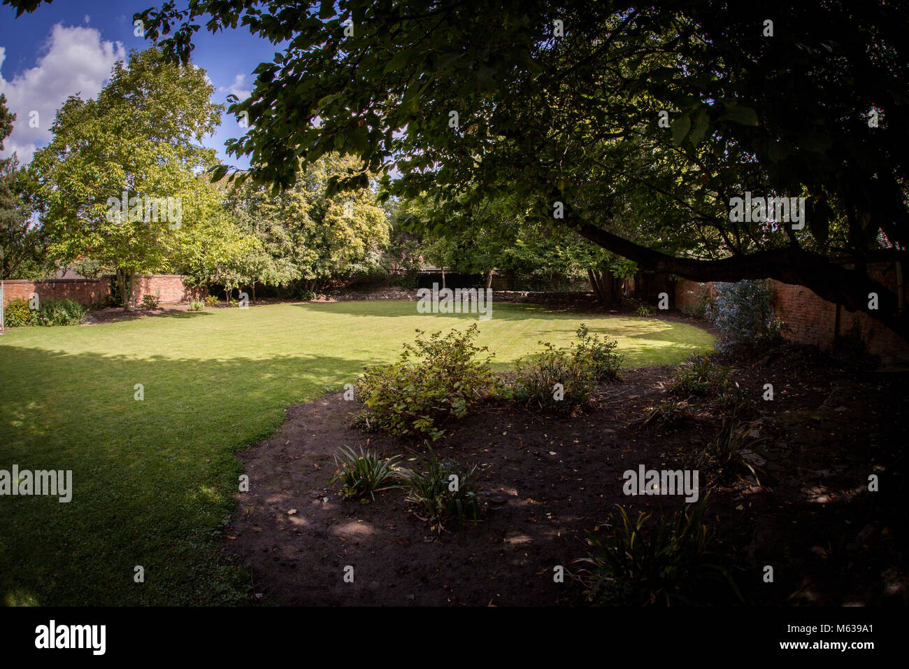 Vista della parete posteriore British giardino con alberi, arbusti e prati Foto Stock