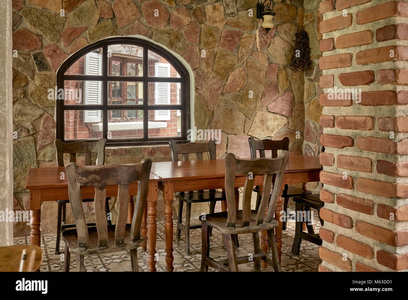 Interno rustico in pietra con tavoli e sedie in legno. Interni del ristorante Vintage con un'accogliente sala da pranzo ad angolo. Foto Stock