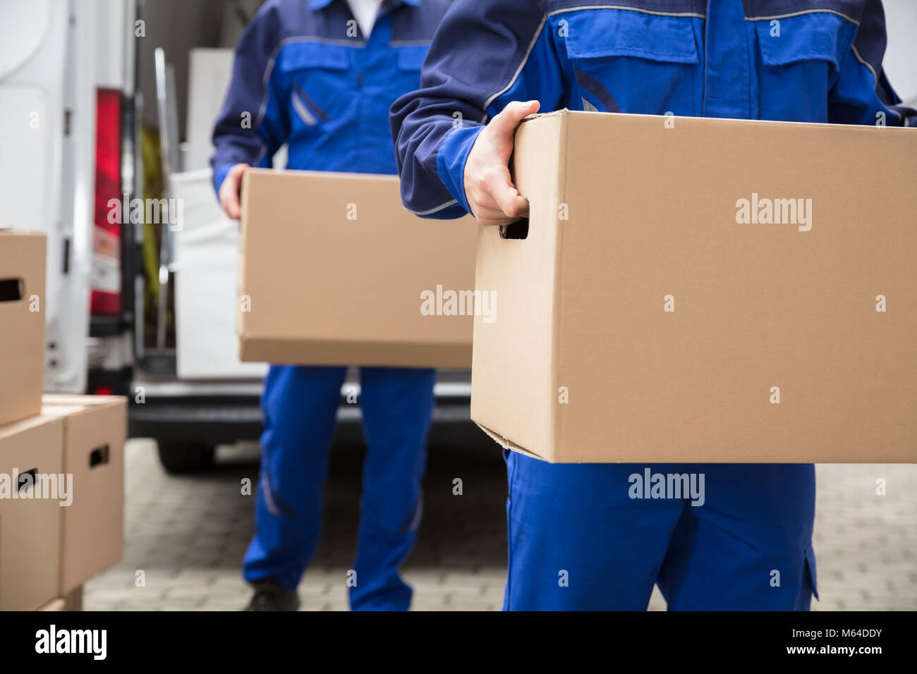 Close-up di due Mover la mano in uniforme che porta una scatola di cartone Foto Stock