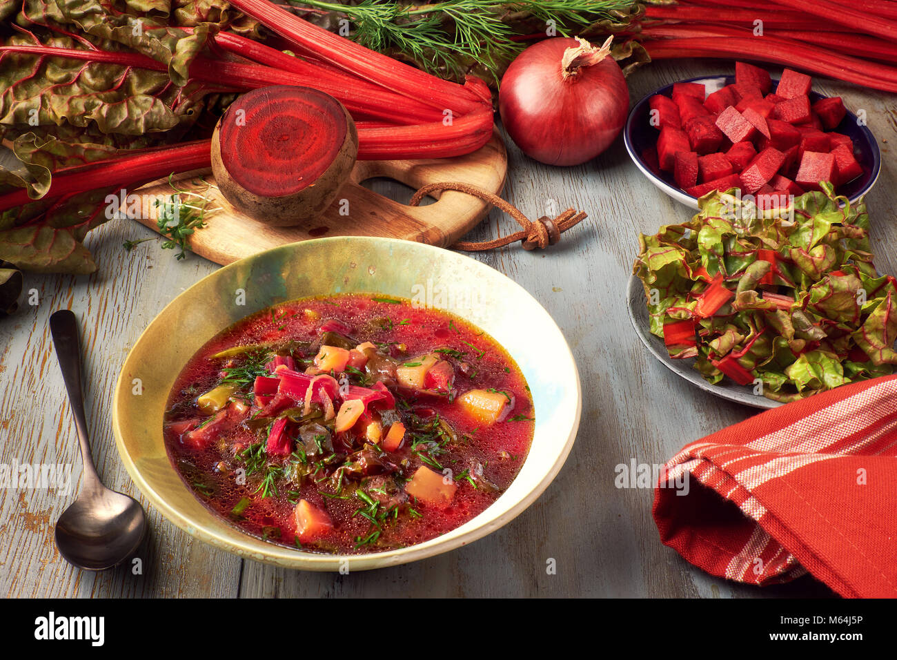 Molla di sfondo alimentare con la barbabietola rossa zuppa di verdure. Ingredienti: rosso radice di barbabietola, fresche foglie di bietola, patate e carote, servita con aneto. Foto Stock