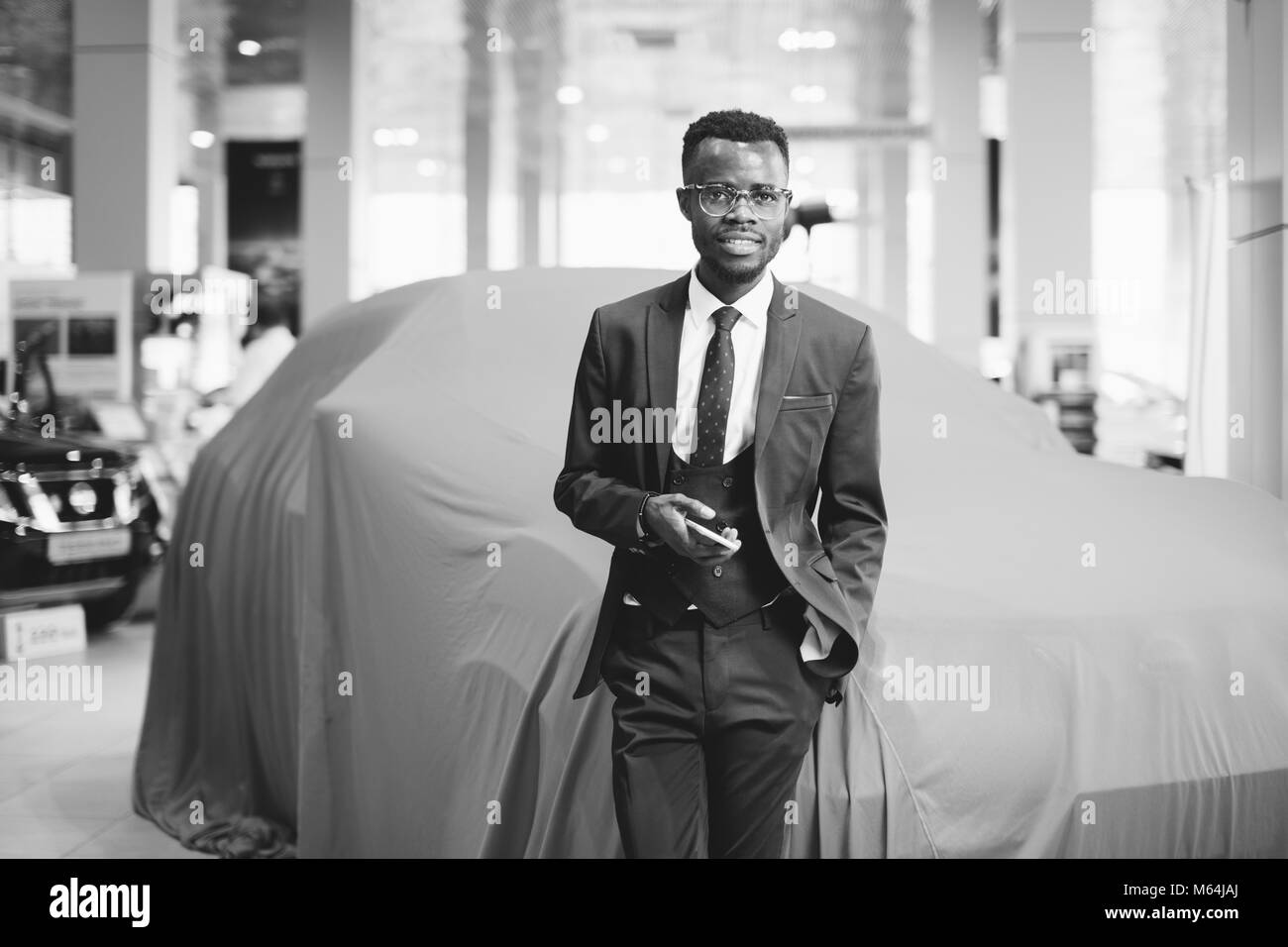 African venditore auto utilizzando smart phone in showroom Foto Stock