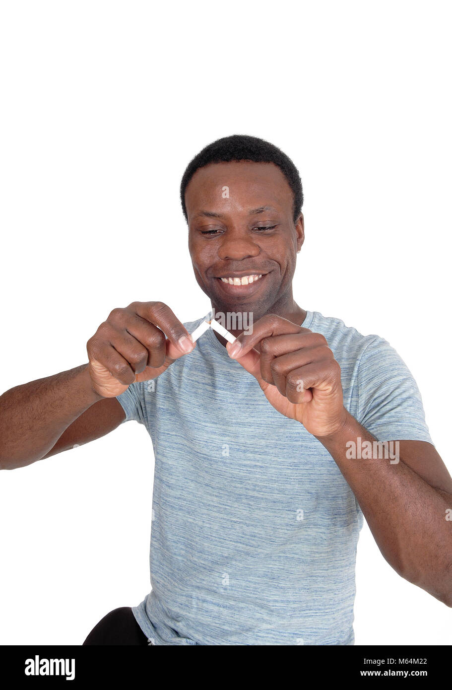 Un bel giovane americano africano uomo in una chiusura immagine è la rottura di una sigaretta è felice di smettere di fumare, isolato su bianco Foto Stock