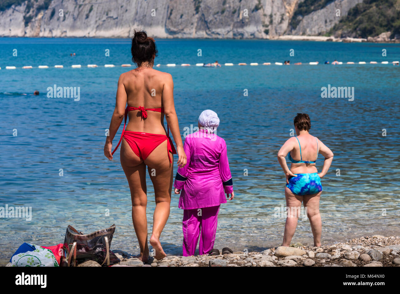 La diversità sulla spiaggia - Vista posteriore del giovane e metà donne  anziane indossando un bikini e burkini con mare azzurro sfondo , il  Montenegro, balcanica Foto stock - Alamy