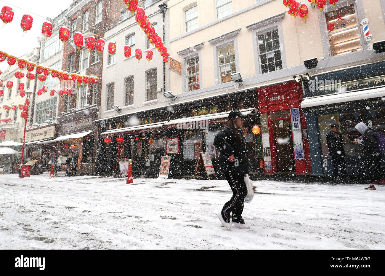 Una donna cammina attraverso la China Town a Londra, come neve pesante e sub-zero condizioni hanno deturpato le strade della Gran Bretagna, le ferrovie e gli aeroporti, con ritardi e cancellazioni. Foto Stock