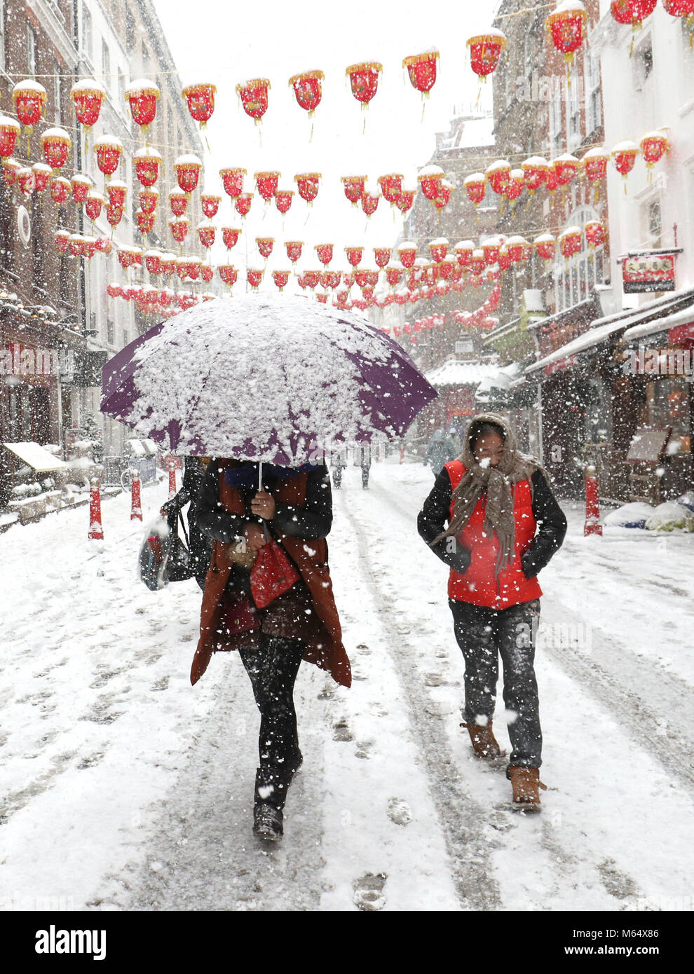 La gente a piedi attraverso la China Town a Londra, come neve pesante e sub-zero condizioni hanno deturpato le strade della Gran Bretagna, le ferrovie e gli aeroporti, con ritardi e cancellazioni. Foto Stock