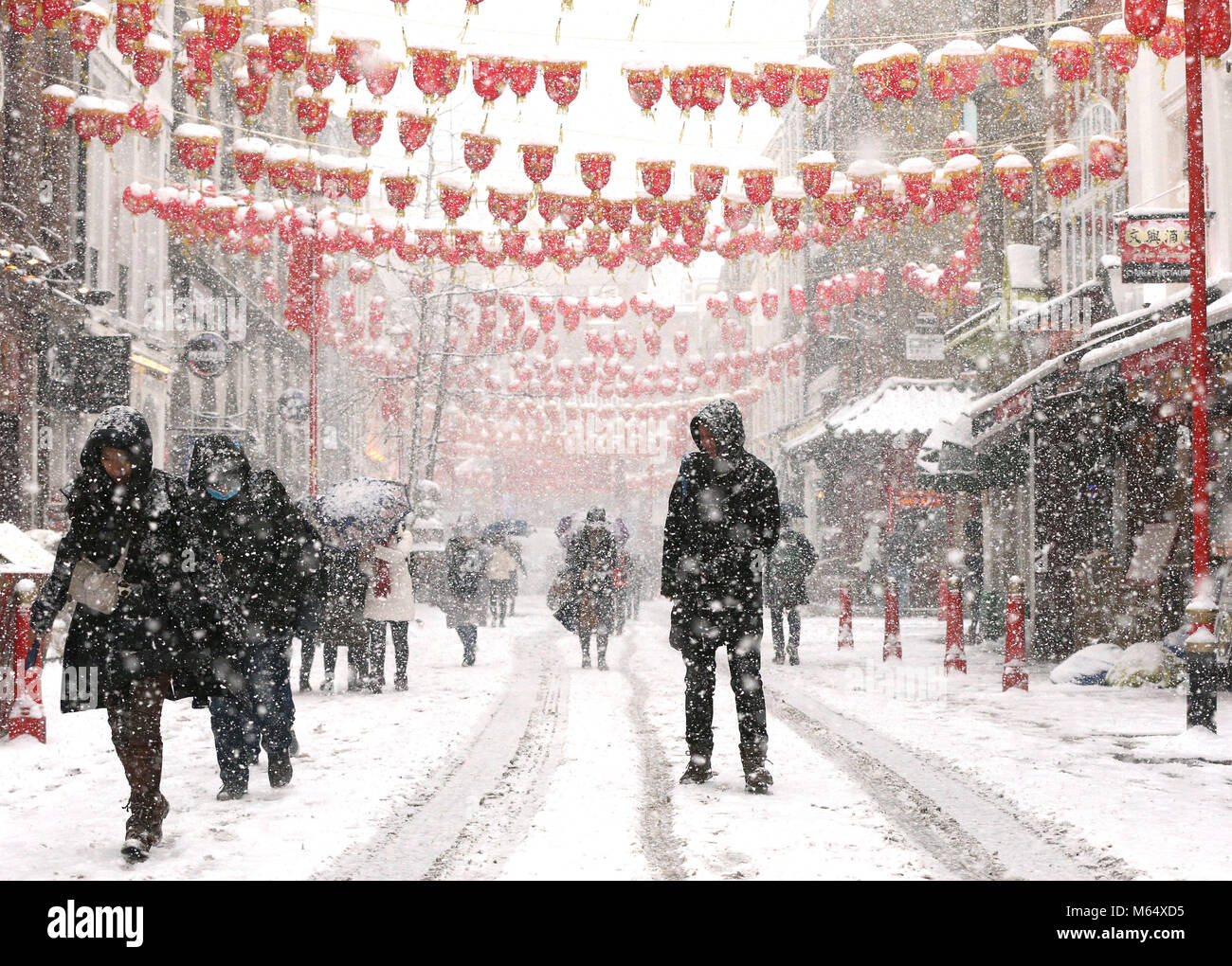 La gente a piedi attraverso la China Town a Londra, come neve pesante e sub-zero condizioni hanno deturpato le strade della Gran Bretagna, le ferrovie e gli aeroporti, con ritardi e cancellazioni. Foto Stock