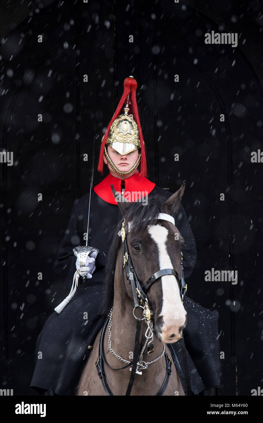 Un membro della cavalleria della famiglia sta di guardia a Horseguards Parade di Londra, come neve pesante e sub-zero condizioni hanno deturpato le strade della Gran Bretagna, le ferrovie e gli aeroporti, con ritardi e cancellazioni. Foto Stock