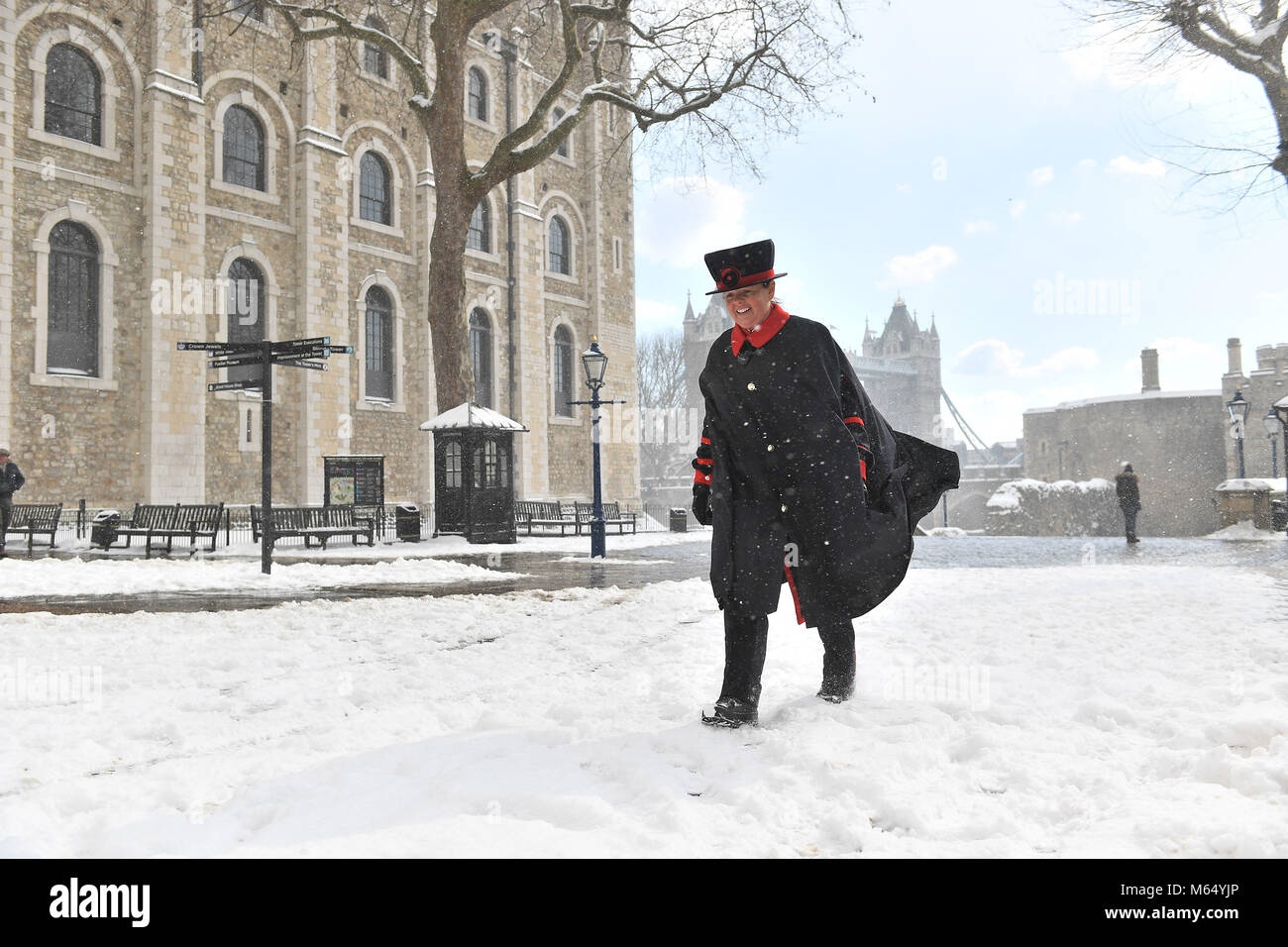 Yeoman Warder Amanda Clark cammina oltre la Torre Bianca alla Torre di Londra in condizioni di neve, come il più alto livello di avvertimento meteo è stato emesso per la Scozia e l'Irlanda, come gli esperti avvertono di condizioni 'come la bizzard'. Foto Stock