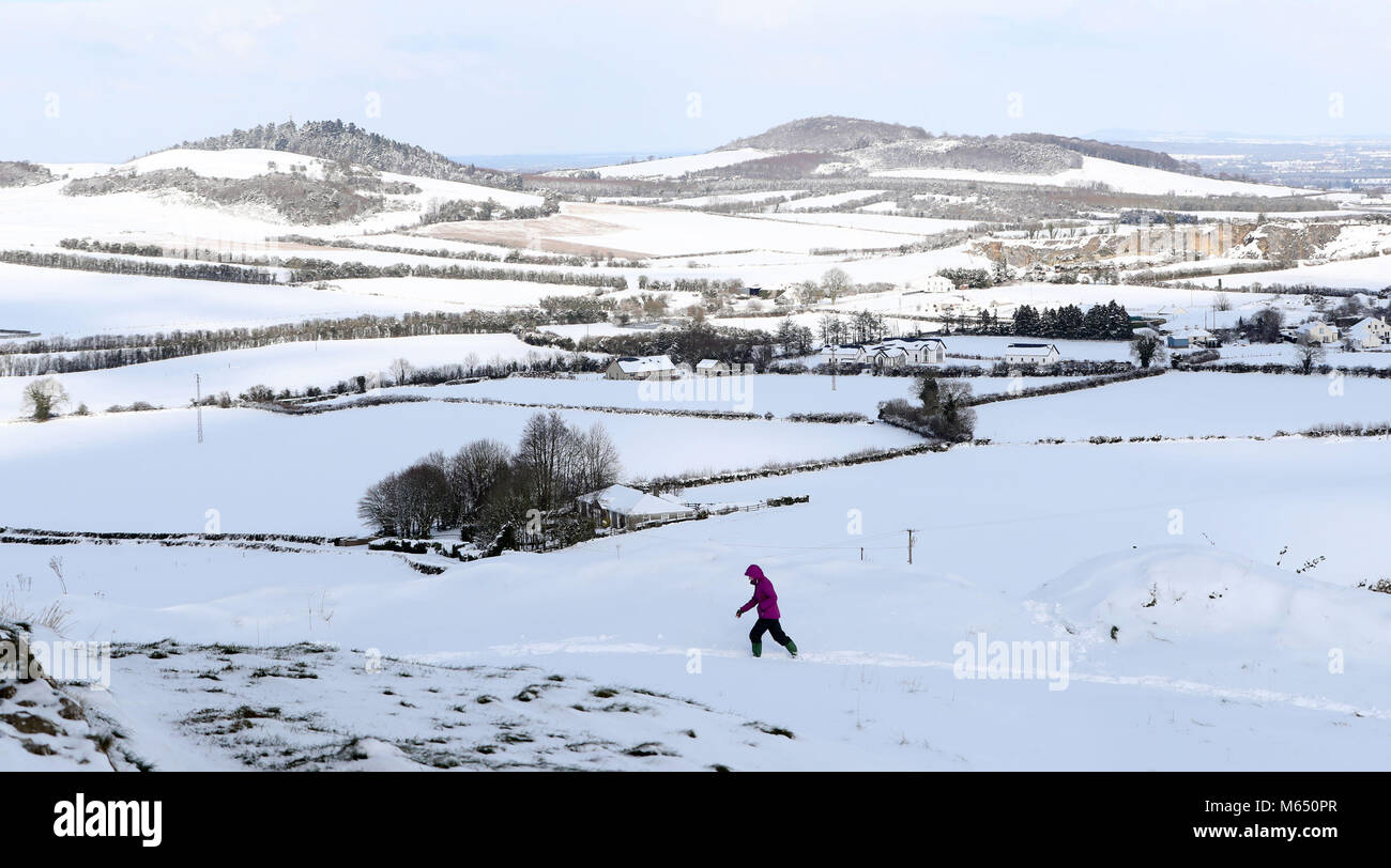 Un viandante vicino al coperto di neve e le rovine del castello di Dunamase sulla roccia di Dunamase in Aghnahily, Co Laois, come condizioni invernali hanno causato più miseria per i viaggiatori per tutta la notte. Foto Stock