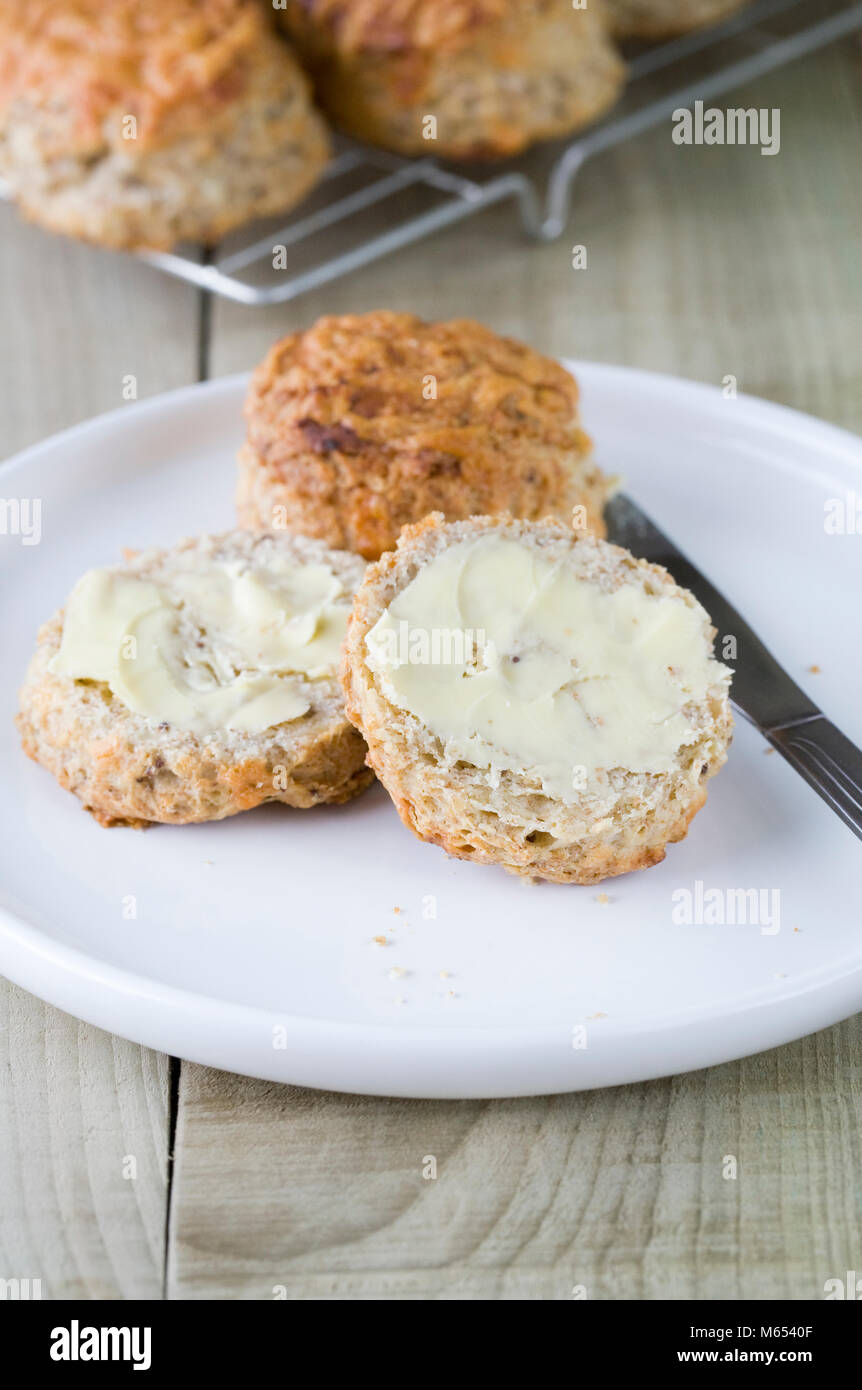 Appena sfornato scones formaggio spalmato di burro. Foto Stock