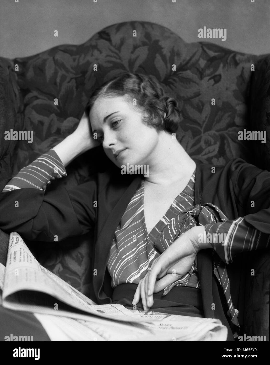 1930s triste donna seduta a schienale alto poltrona indossando Camicia a  Righe testa PENDENTE A PORTATA DI MANO IL GIORNALE IN GIRO - g4749 HAR001  HARS pensieroso riflessivo all'interno di strisce mal