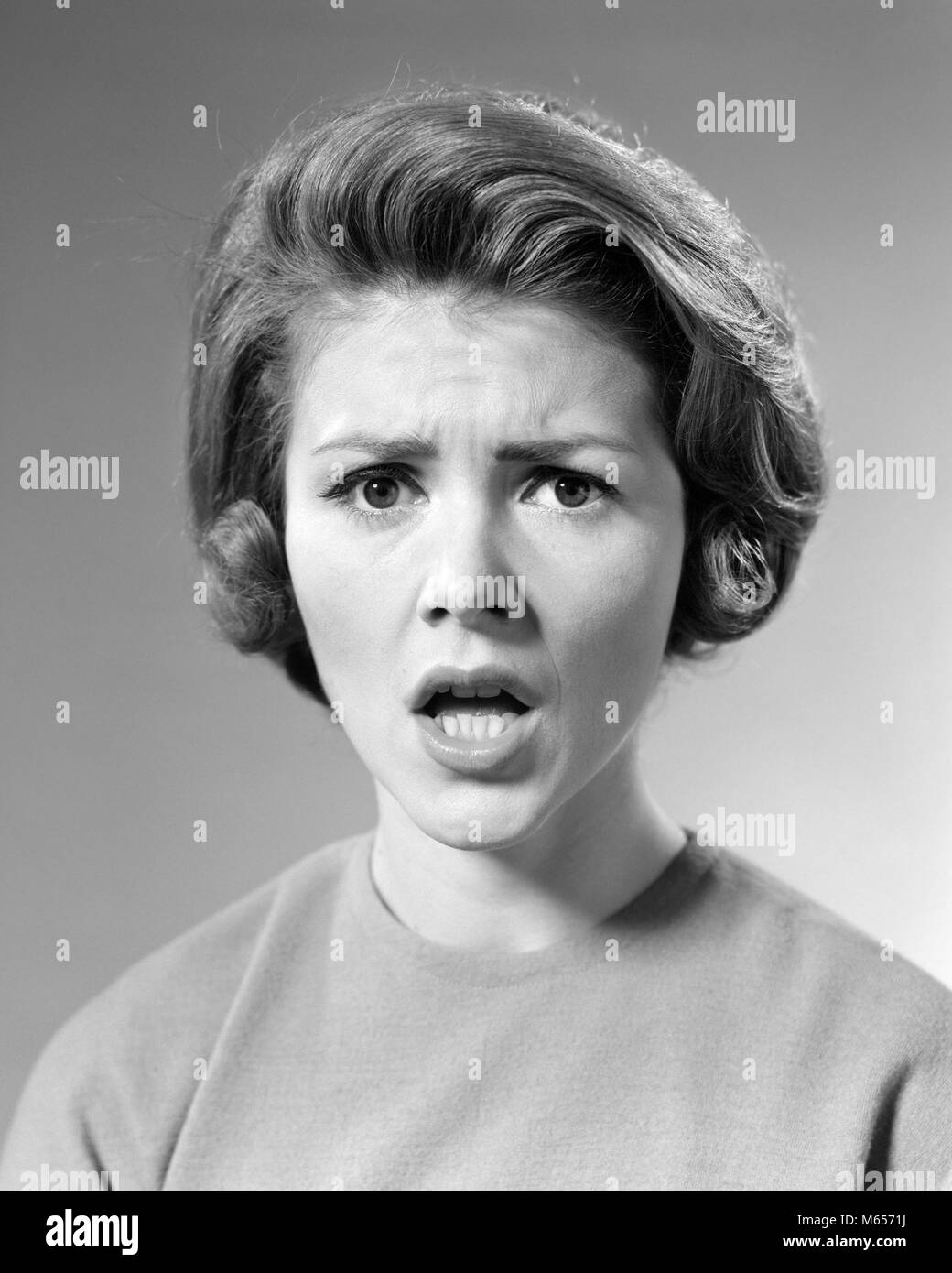 Anni sessanta BRUNETTE DONNA CON scioccato arrabbiato grave espressione facciale guardando telecamera - g5856 HAR001 HARS EMOZIONI MID-adulto metà donna adulta allarmato B&W in bianco e nero di etnia caucasica guardando la telecamera OH NO in vecchio stile persone Foto Stock