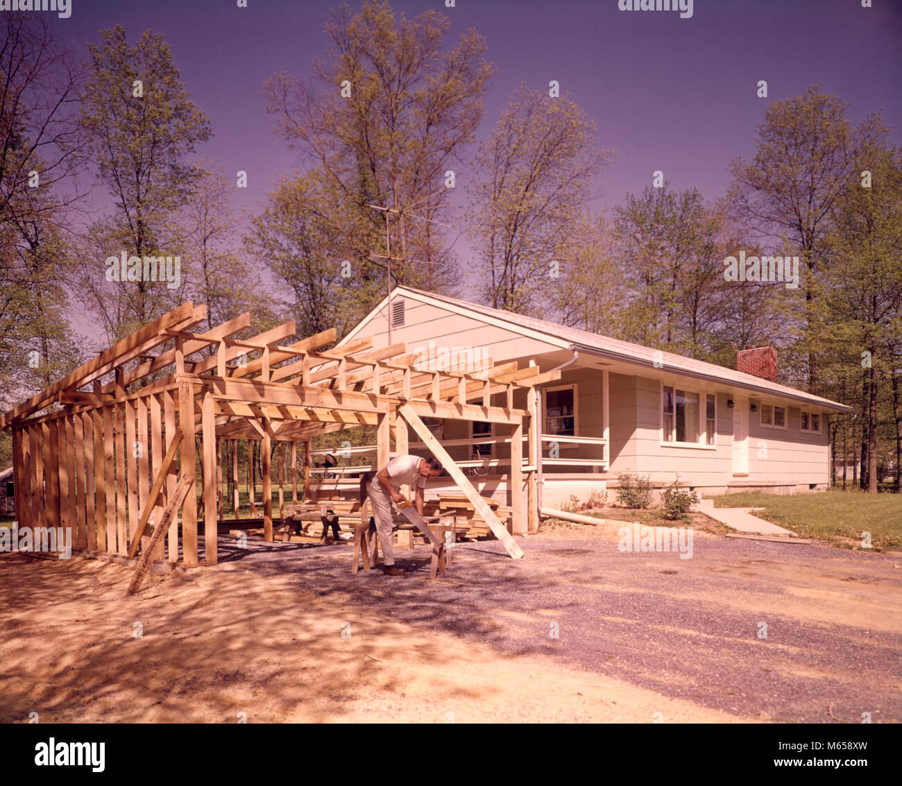 Anni sessanta uomo CARPENTER segatura di legno Costruzione casa aggiunta di due garage auto - KB4528 HAR001 HARS legname maschi occupazioni di sezionatura in vecchio stile persone ranch house in stile ranch Foto Stock