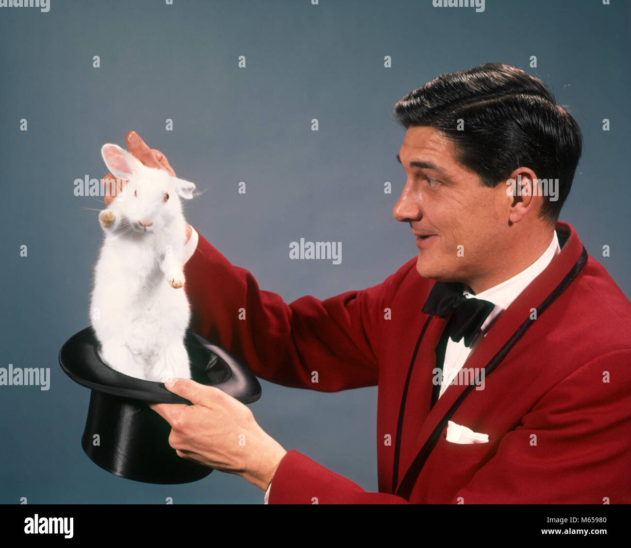 Anni sessanta anni settanta uomo mago indossare tuta rossa tirando il coniglio bianco AL DI FUORI DEL TOP HAT - kc2832 HAR001 HARS LAVORI STUDIO SHOT UNA SOLA PERSONA spazio copia di metà lunghezza carattere animali all'interno della professione di fiducia di intrattenimento NOSTALGIA 30-35 anni 35-40 anni performing arts UN ANIMALE MAGHI PEOPLE STORY OCCUPAZIONE SPECIALITÀ ILLUSIONE COMPETENZE PERFORMER CARRIERE caratteri emozione intrattenitore attori artisti intrattenitori testa-ware magico coniglio bianco creatura LEGERDEMAIN MASCHI MAMMIFERO MID-adulto metà uomo adulto roditore top hat etnia caucasica occupazioni in vecchio stile persone prestidigitazione Foto Stock