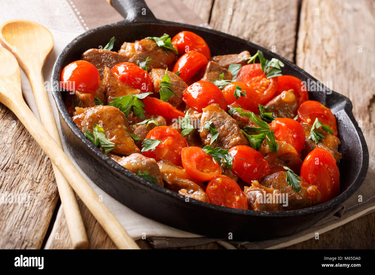Alimenti biologici: carne in salsa piccante con pomodori verdi e close-up su una padella su una tavola orizzontale. Foto Stock
