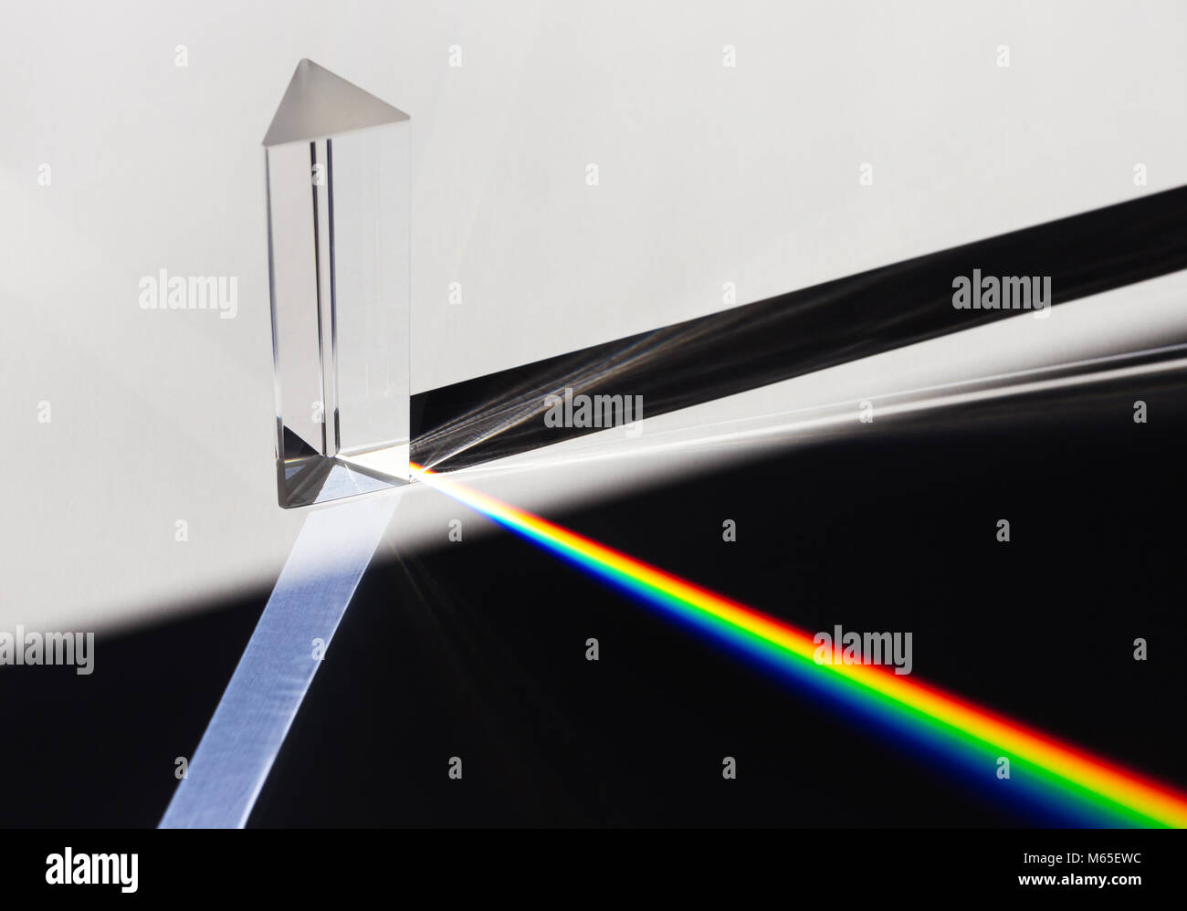 Un prisma disperde la luce del sole si divide in un spettro su uno sfondo bianco. Foto Stock