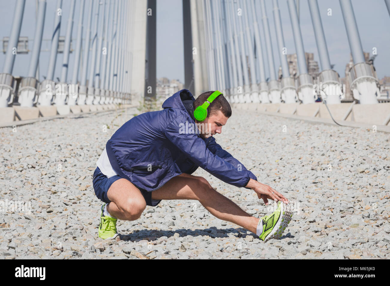 Atleta runner indossa le cuffie durante il riscaldamento facendo esercizio di stretching Foto Stock