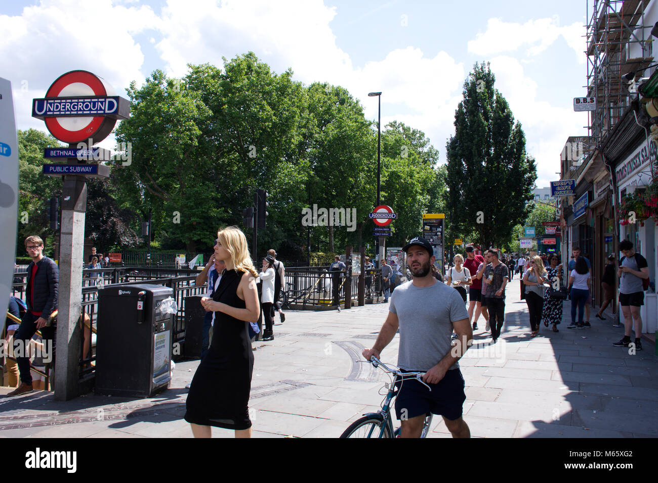 Le persone al di fuori di Bethnal Green tube station su soleggiate giornate estive.London,Uk.Street,urban,real,autentica di persone,editoriale.vita londinese,segno della metropolitana. Foto Stock