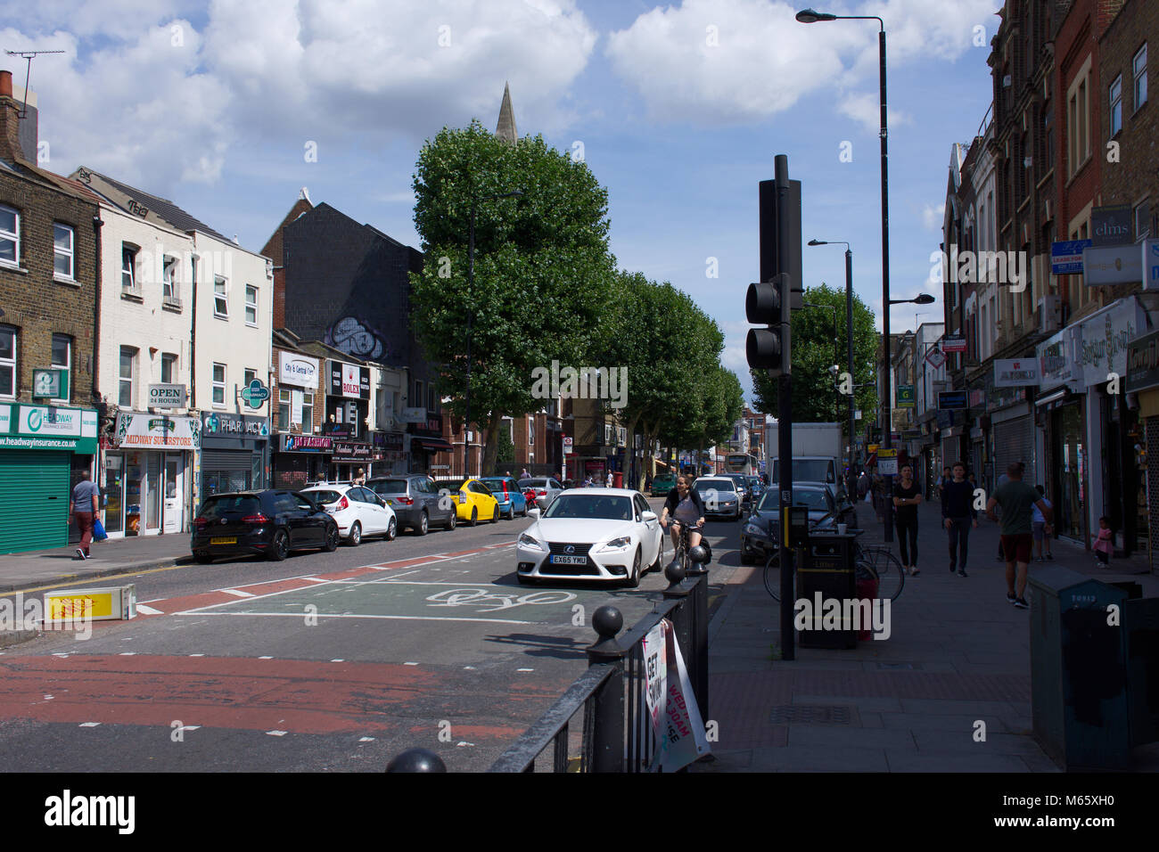 Bethnal Green,High Street,sul giorno di estate.Street,edifici,auto persone casualmente a piedi.London,Oriente,Regno Unito.Un lato della strada in ombra.6.08.2017. Foto Stock