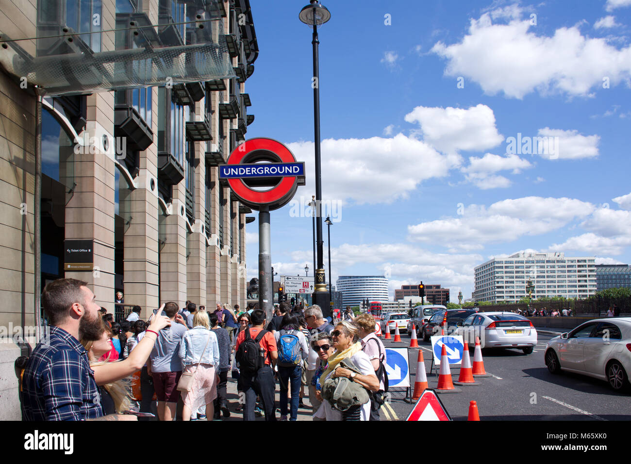 Le persone al di fuori della stazione di Westminster a Londra,Inghilterra.Hipster guardando l uomo e la donna puntando il dito in Big Ben direzione.opere stradali e del traffico. Foto Stock