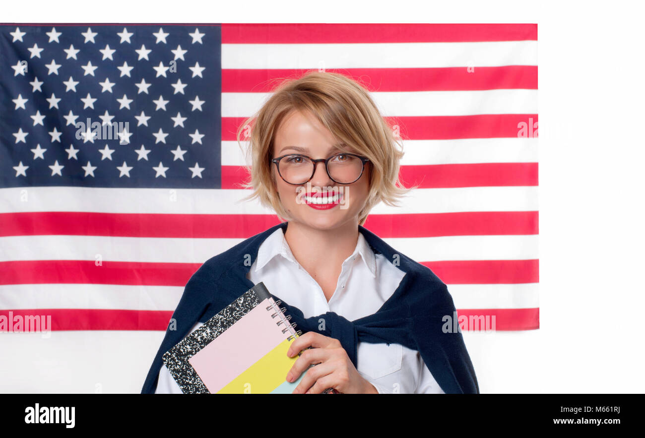 Sorridente ragazza su Stati Uniti bandiera dello sfondo. Studente è di apprendimento della lingua inglese come lingua straniera. Bandiera americana. Foto Stock
