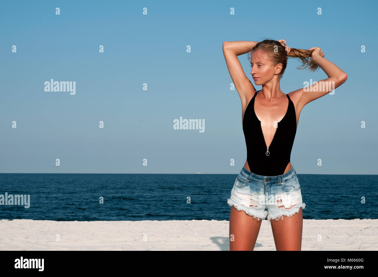 Bella donna in costume nero e jeans corti sulla spiaggia. Concetto di  estate Foto stock - Alamy
