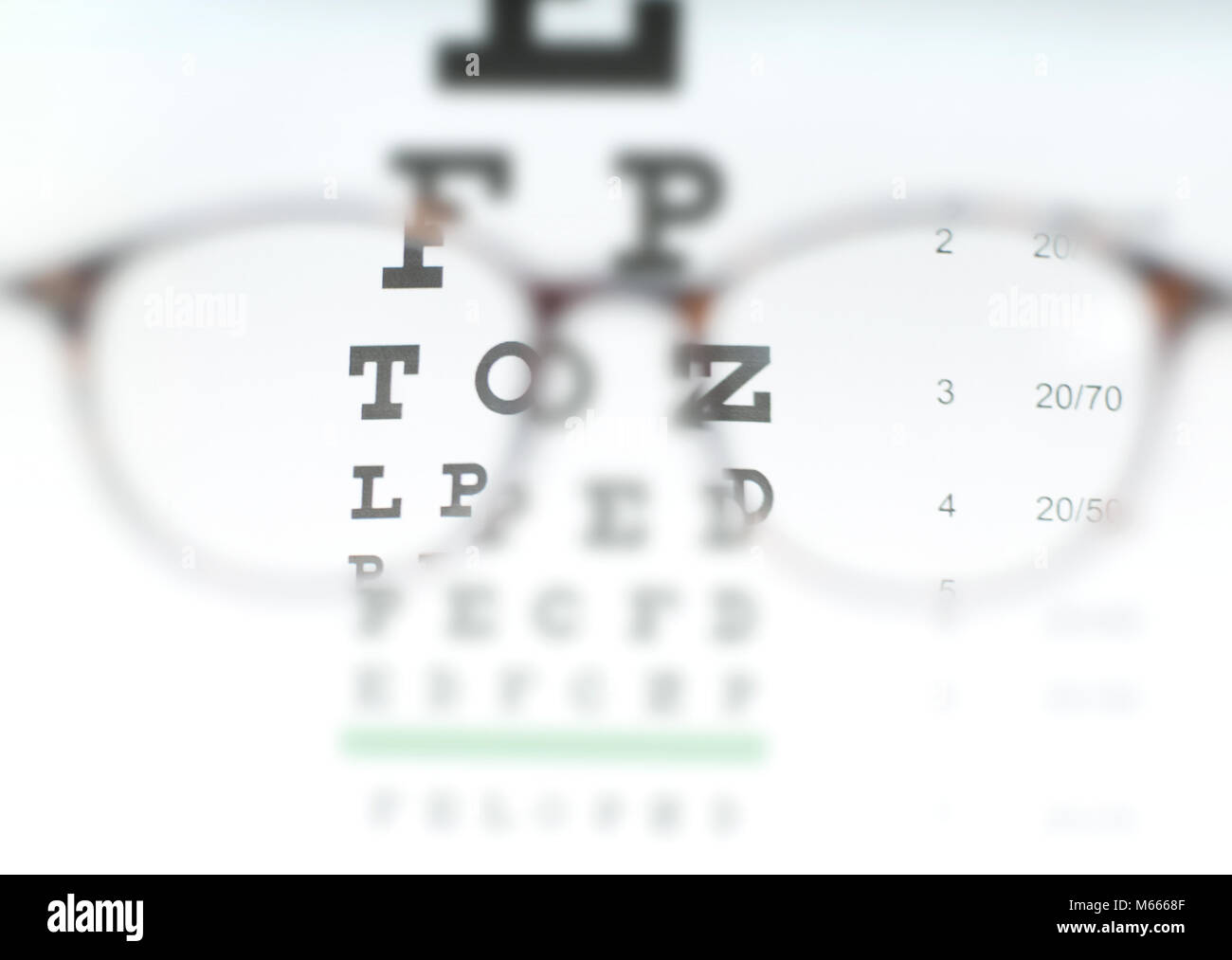 Visione della tabella di dati di prova visto attraverso gli occhiali dell'occhio. La prescrizione di occhiali seduto su un occhio tabella di dati di prova Foto Stock