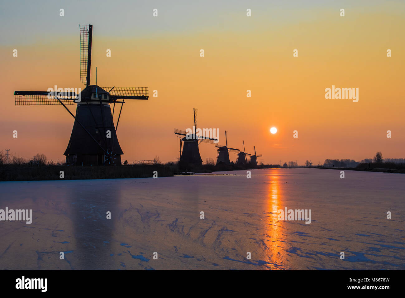Sunrise in una fredda giornata invernale presso i mulini a vento al sito del patrimonio mondiale Kinderdijk nei Paesi Bassi Foto Stock