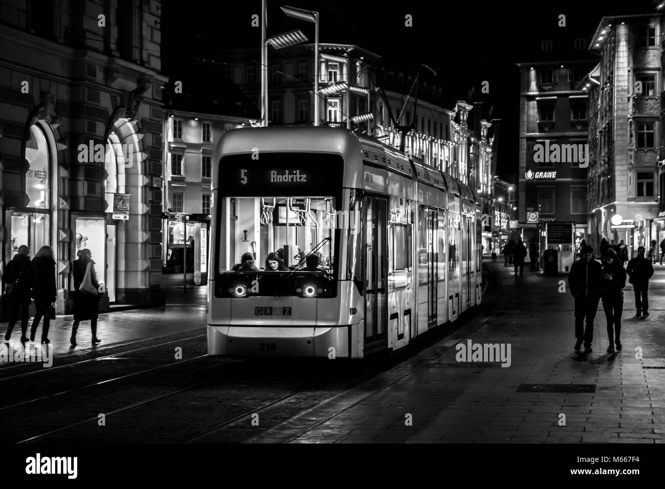 Graz, Austria - 08.02.2018: tram numero 5 arriva alla piazza principale stazione di notte (nero / bianco) Foto Stock