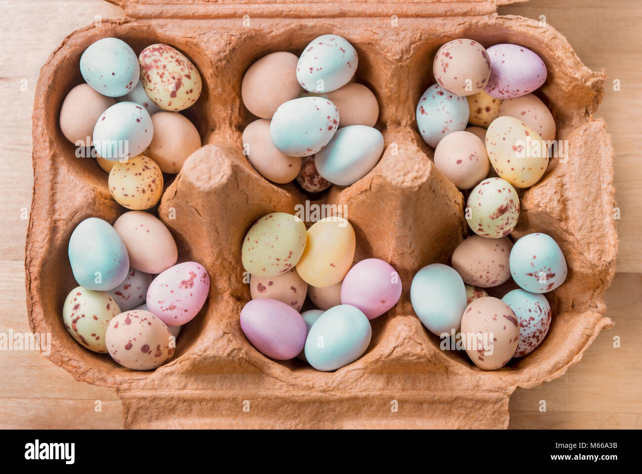 Vista aerea di un aperto marrone cartone uovo, riempito con pile di piccole a forma di uovo di pasqua dolci. Foto Stock