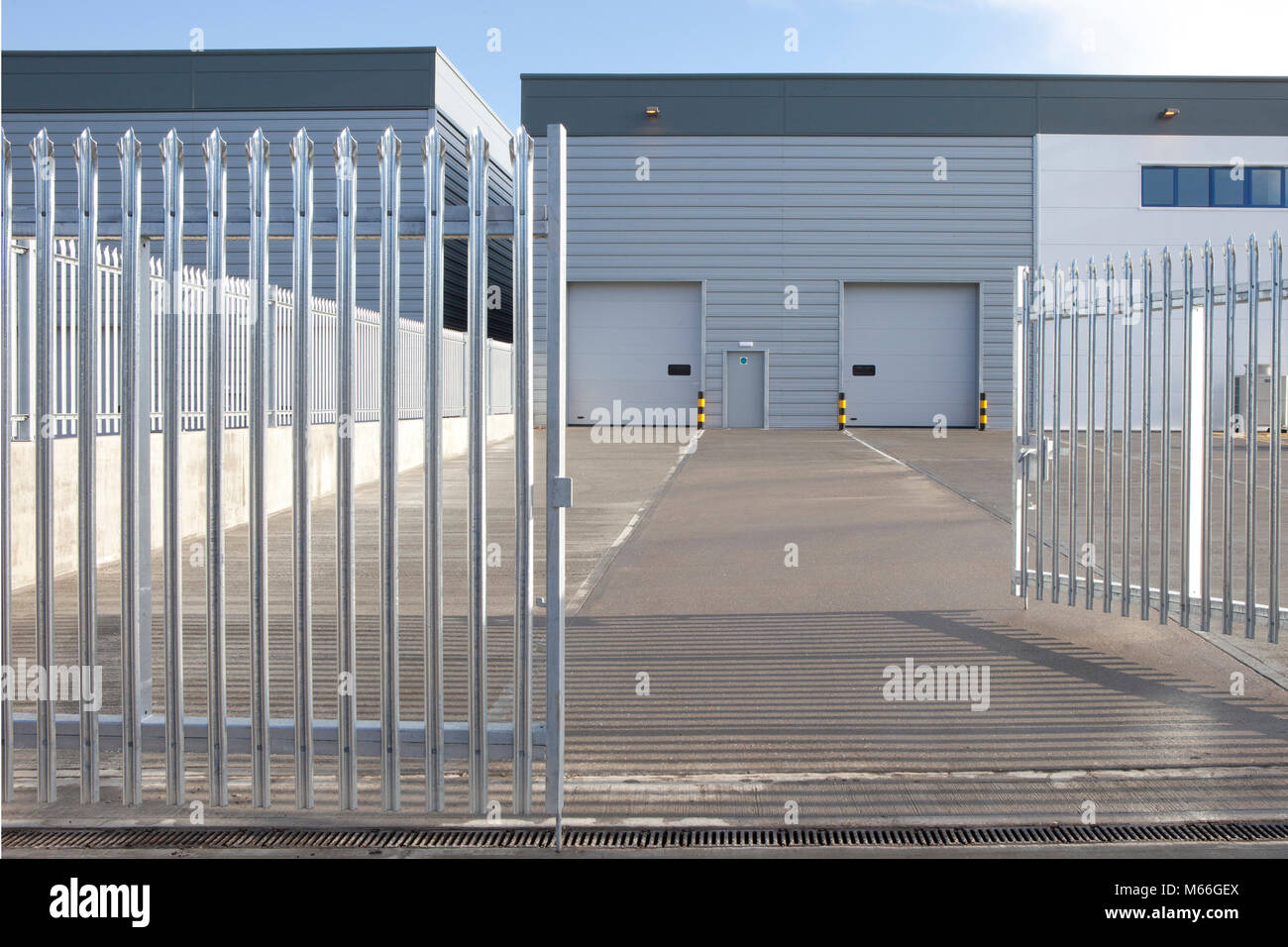 Nuovo magazzino di deposito la placcatura in metallo e il caricamento della baia di cielo blu e la recinzione di sicurezza graphic cercando angolo. Foto Stock