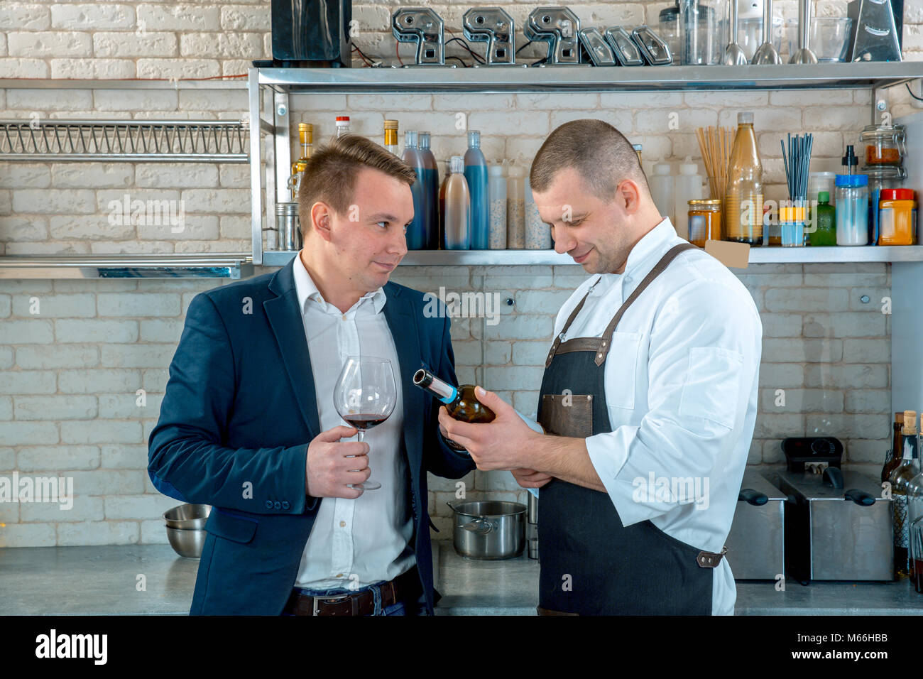 Sommelier e chef discutere di vino sulla cucina interno. Il sommelier consiglia lo chef per avere un vino rosso che si adatta perfettamente al piatto. Degustazione di vino rosso Foto Stock