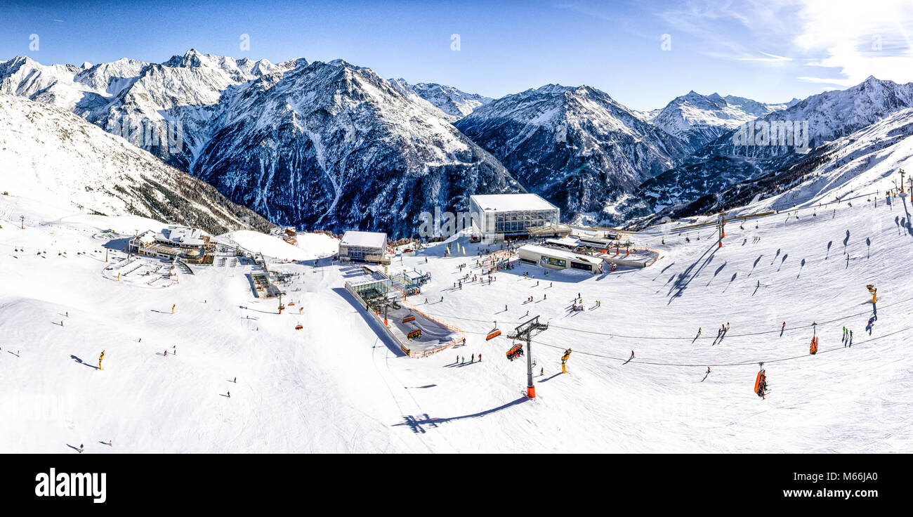 Panoramica vista aerea della località sciistica nelle Alpi con impianti di risalita e la gente lo sci sul pendio Foto Stock