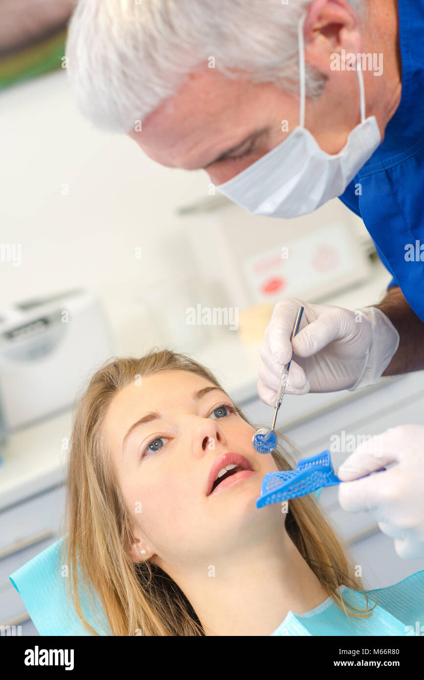 Dentista in bilico per ispezionare denti del paziente Foto Stock