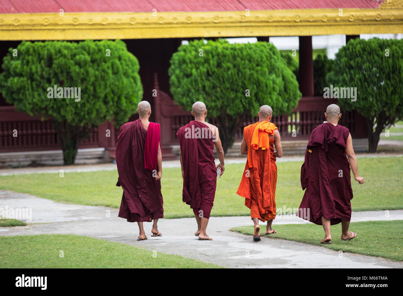 Quattro giovani monaci a piedi all'interno del Mandalay Royal Palace complesso, Myanmar (Birmania). Foto Stock